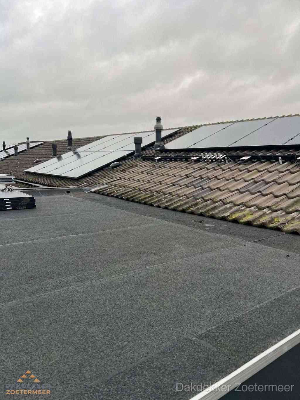 Plat dak inspectie met bitumen bedekking naast schuin pannendak in Zoetermeer
