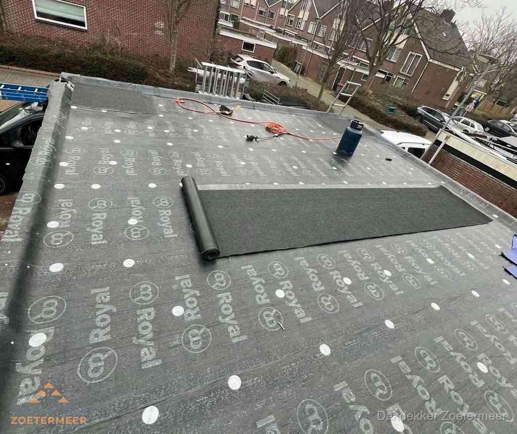 Dakdekker aan het werk met gasbrander op plat bitumen dak in Zoetermeer